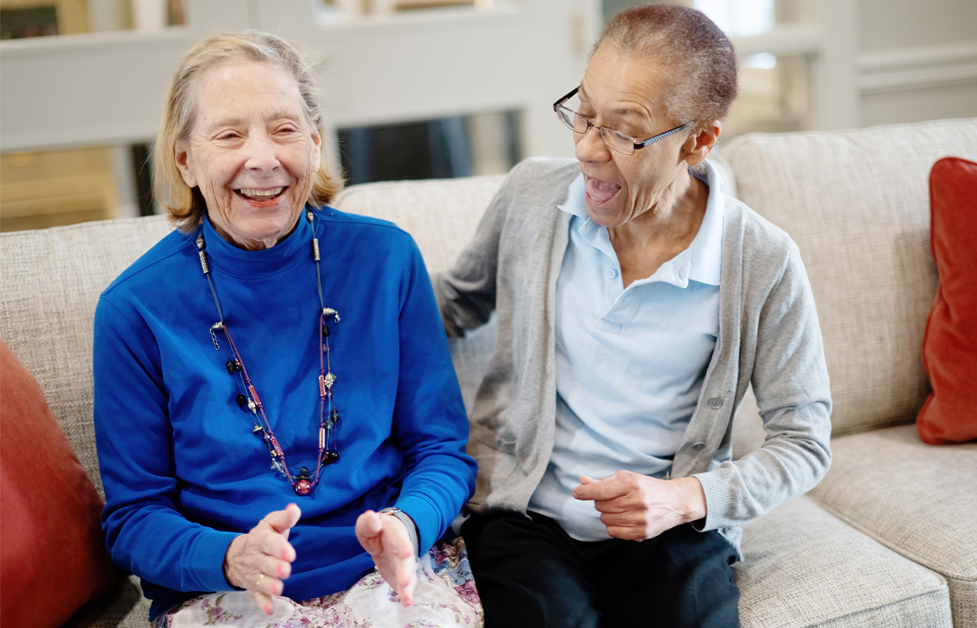 Two people sitting on a couch laughing.