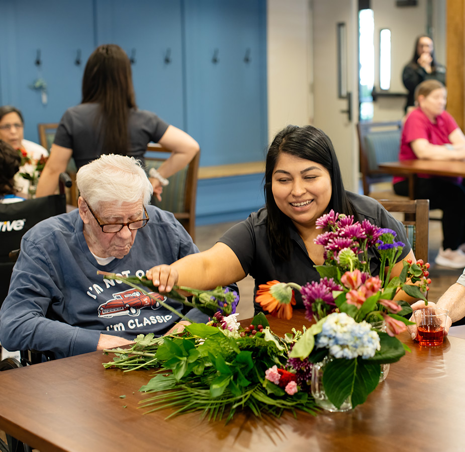 An associate helping a resident with flower arrangement.
