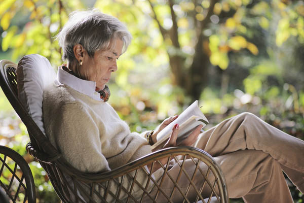 Pensive woman reads book while sitting on a cozy chair.