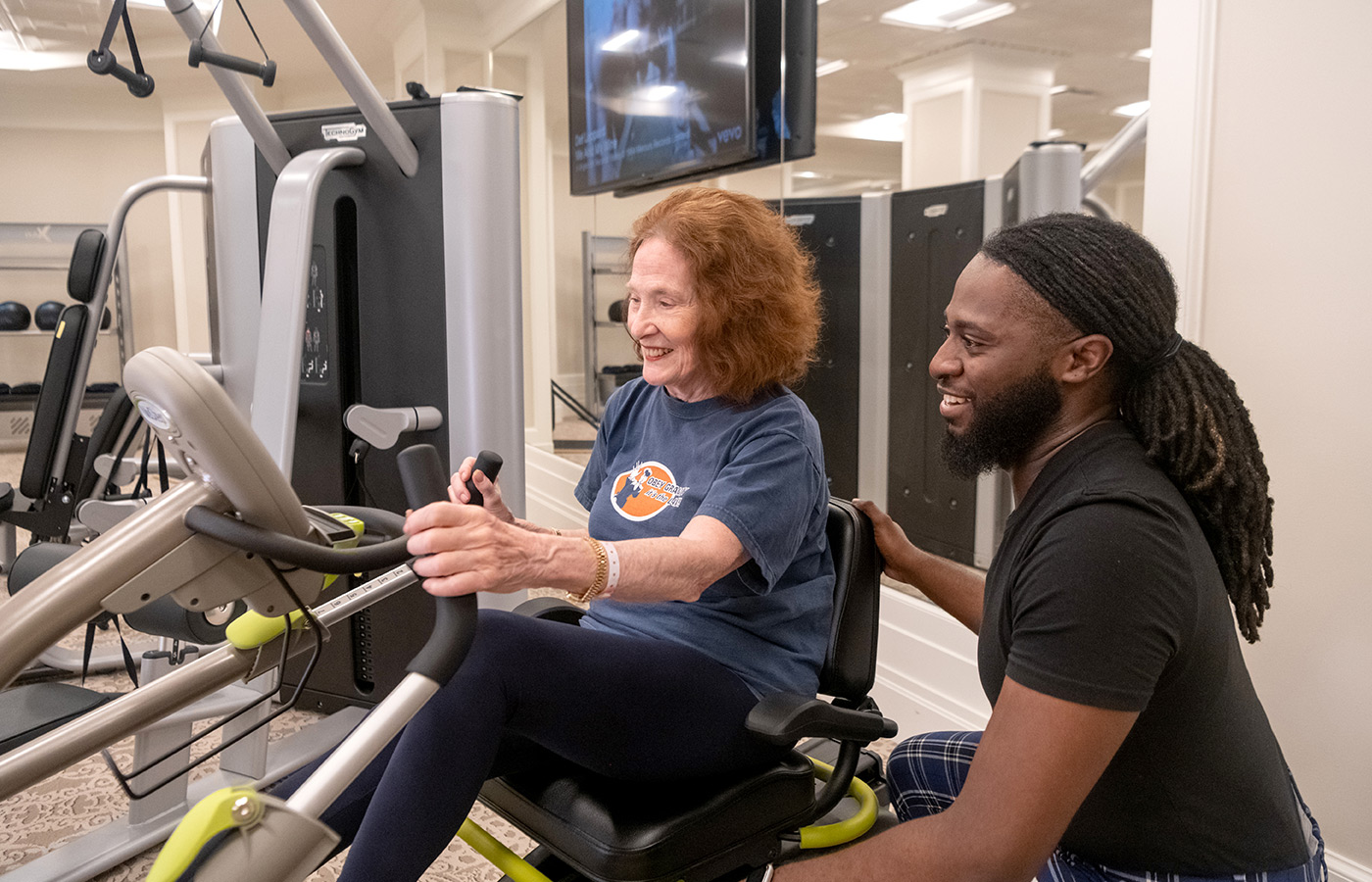 A resident getting help from an associate at the gym.