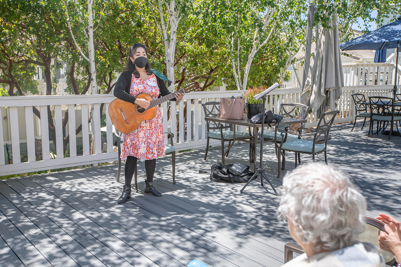 Female musician plays guitar for seniors.