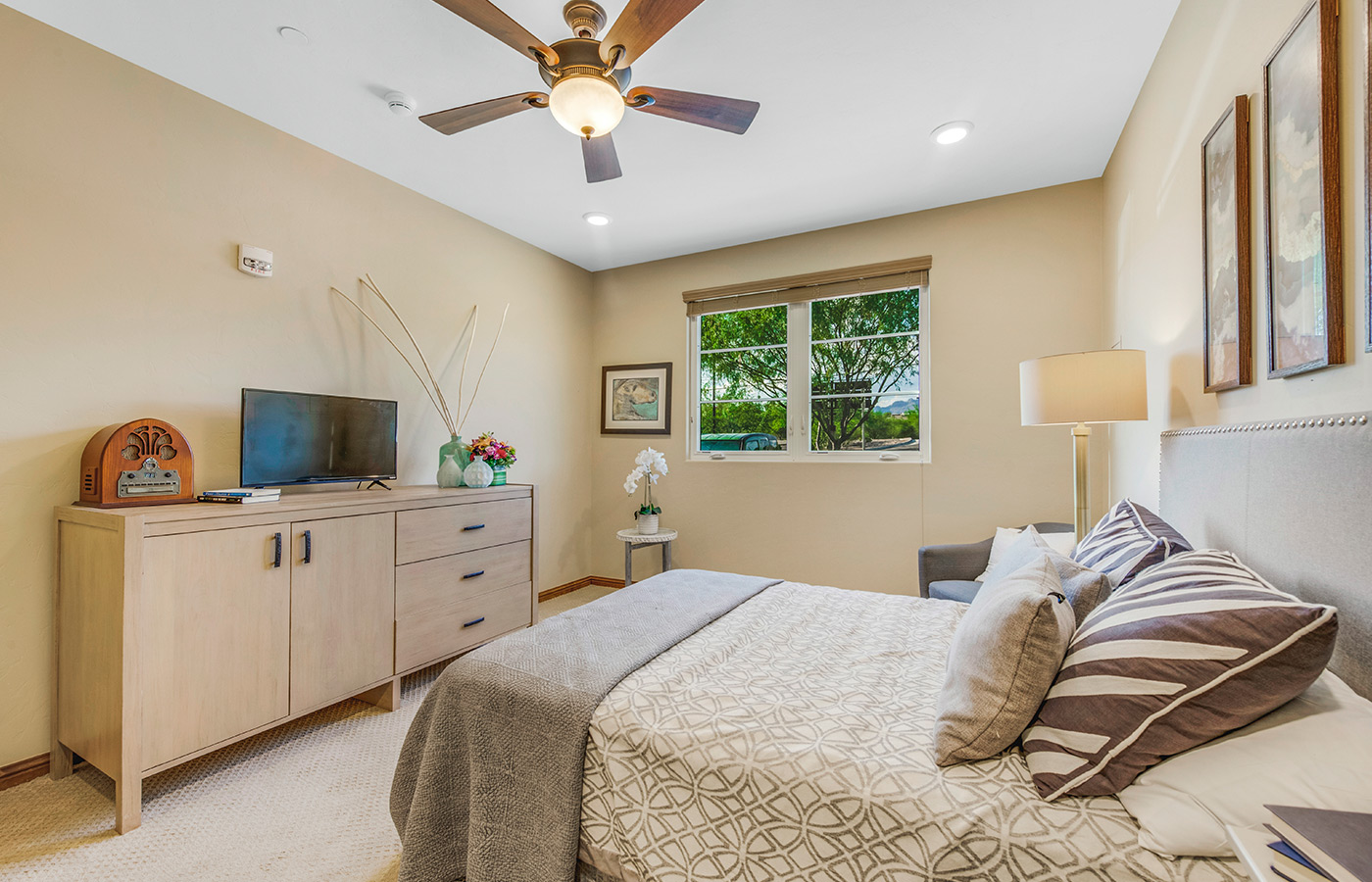 Furnished bedroom with bed and window and fan.