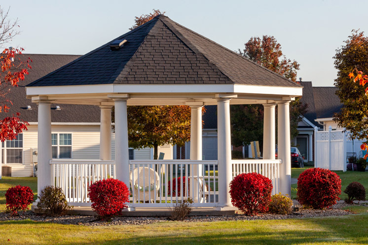 Gazebo surrounded by bushes and flowers.