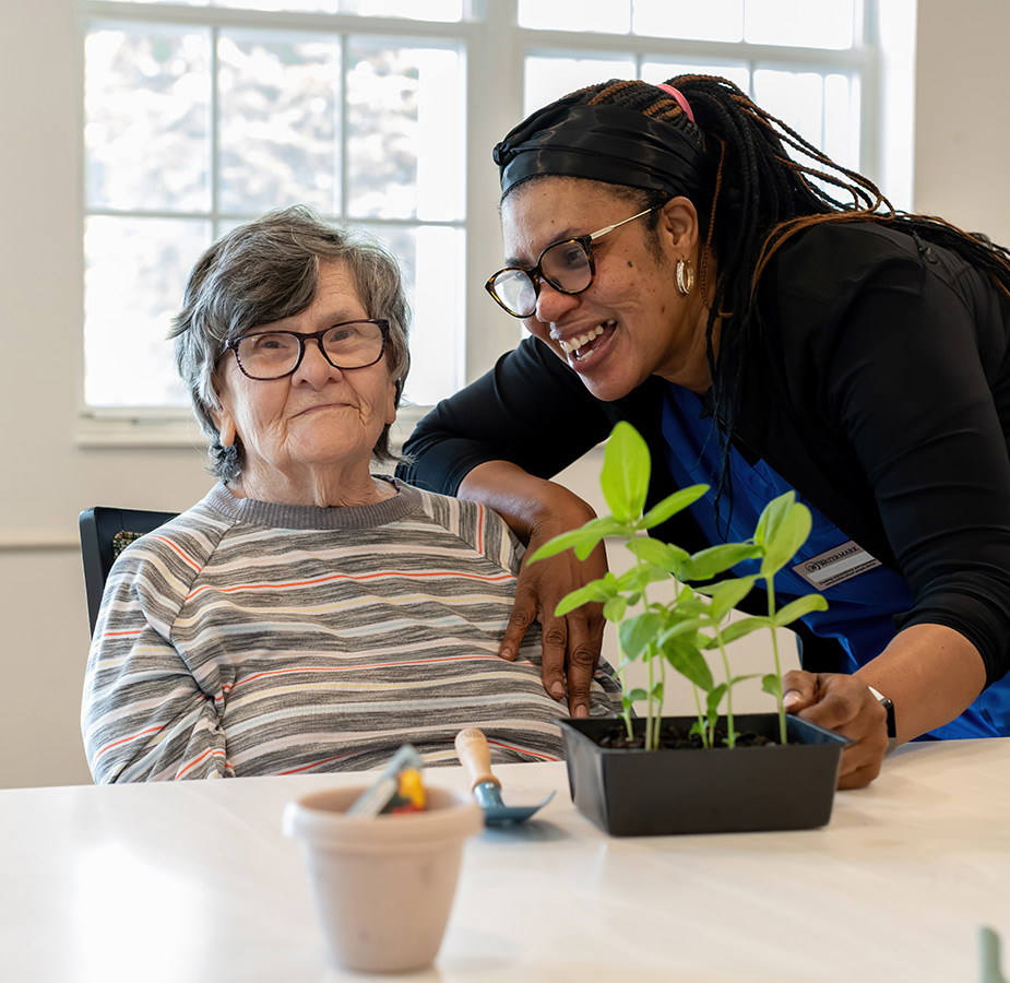 A caregiver working with a resident at a gardening bench.