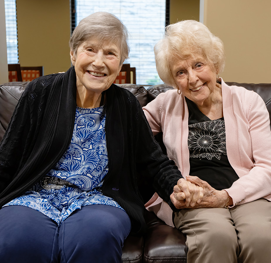 Two friends holding hands on the couch.