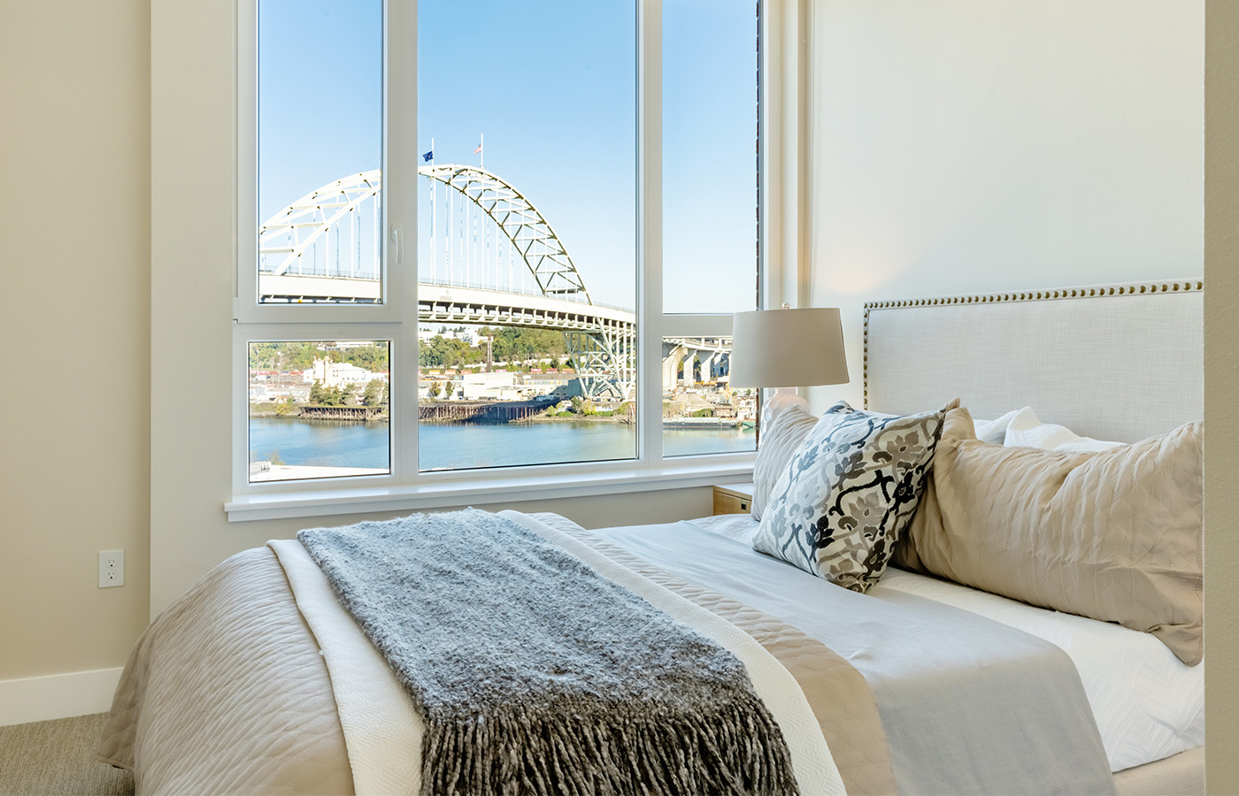 A fully furnished bedroom with a view of the river outside the window.