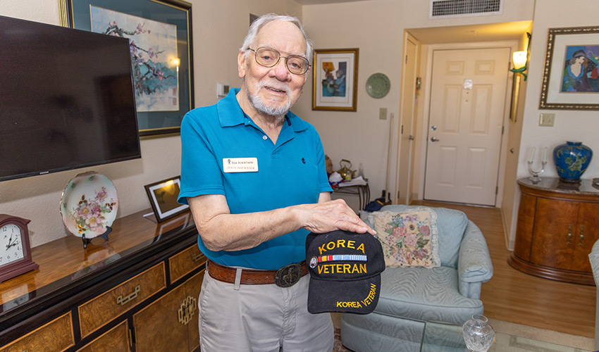 A senior man showing his veteran hat.
