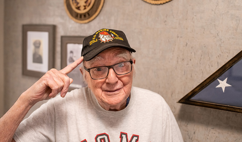 A senior veteran pointing to his hat.