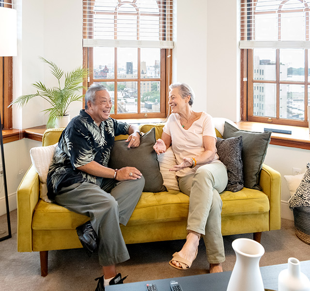 Residents laughing while sitting down on a comfy yellow sofa.