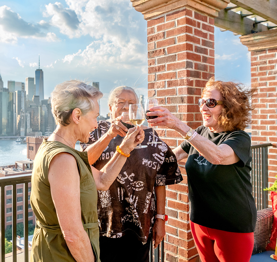 Three residents toasting with drinks on the rooftop.