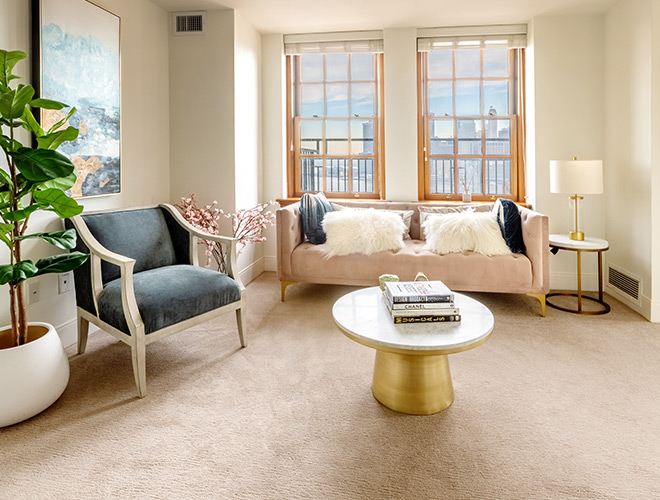 The terrace apartment living room with a couch, chair, and views of the city out the window.