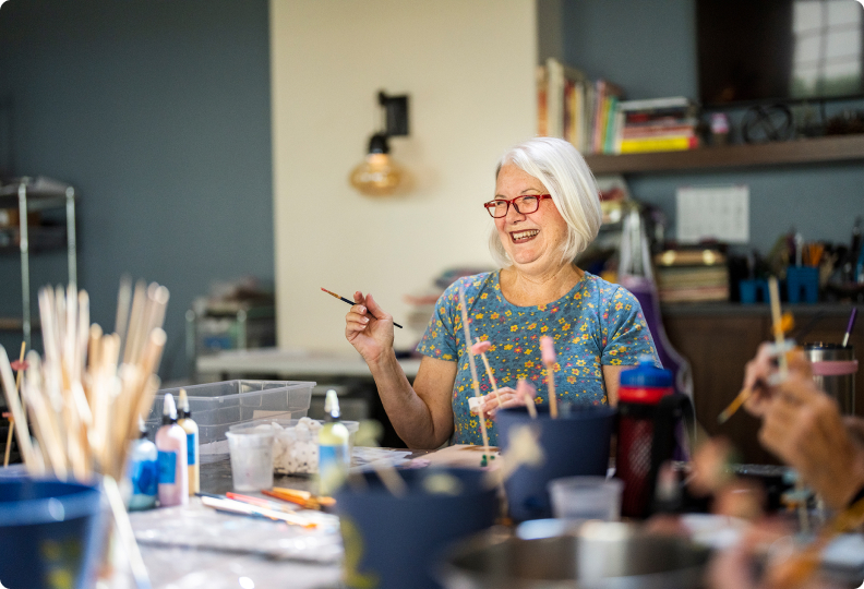 A resident laughing while holding a paintbrush.