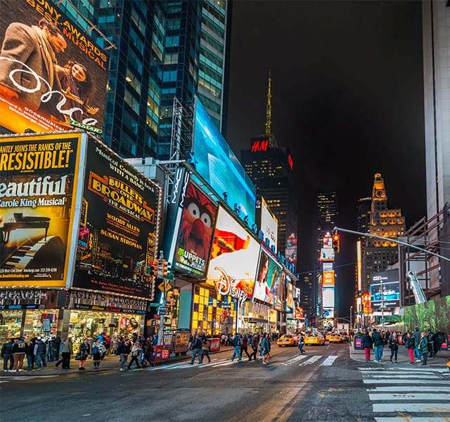Broadway street with lit up signs at night.