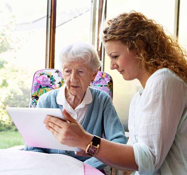 An associate assisting a resident with a tablet.