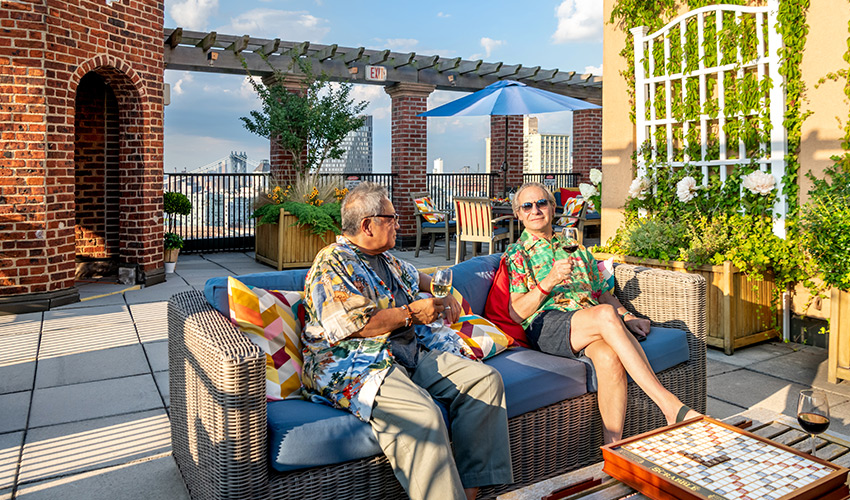 Two senior men enjoying drinks seated in the rooftop garden.