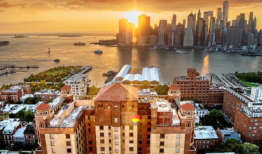 Aerial view of Brooklyn Heights with the harbor in the background at sunset.