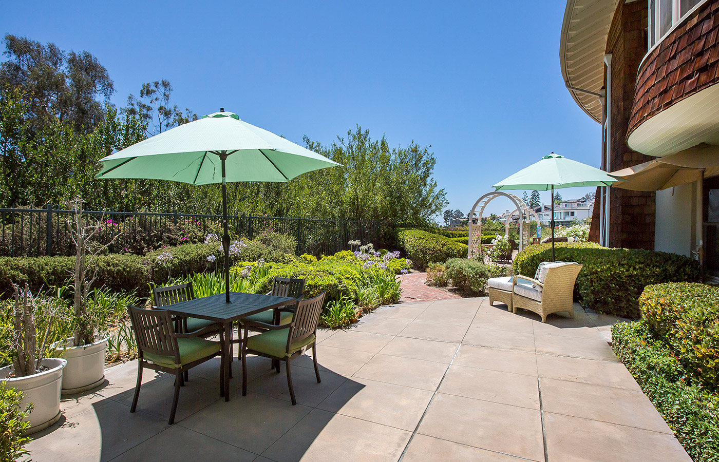 Patio and garden with tables, chairs and umbrellas.