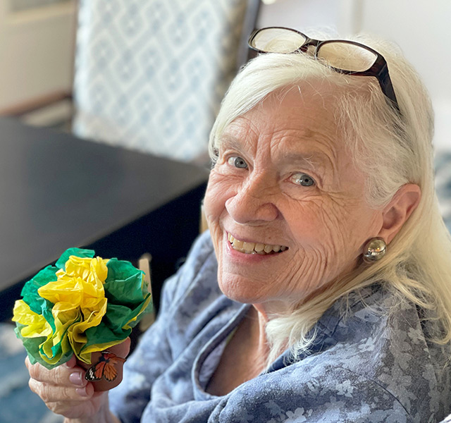 Resident holding green and yellow flowers.