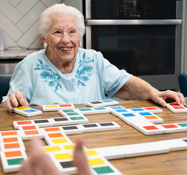 A resident is playing a game at a table in the activity room.