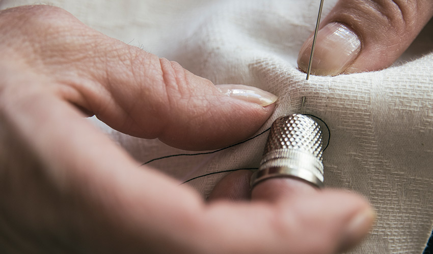 Close up of hands sewing fabric.