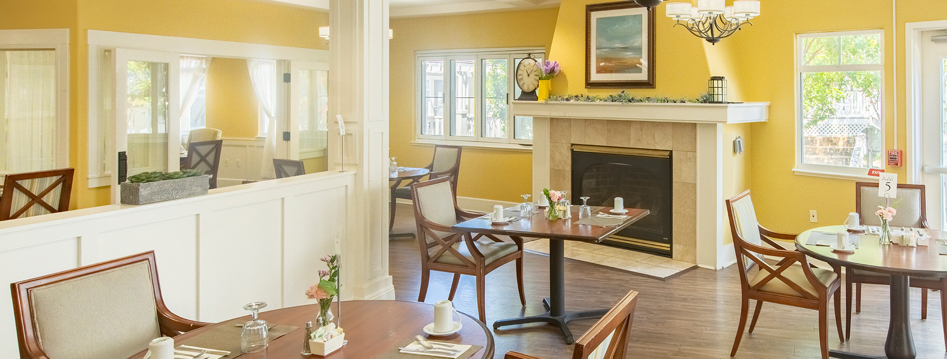 A bright sunny dining room with tables set for breakfast.