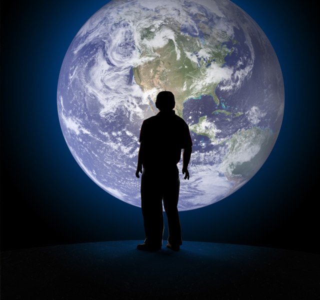 Shadowy figure standing in front of the planet earth.