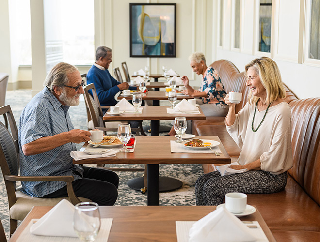 Two residents are enjoying their meals together in a dining area at The Watermark at Houston Heights.