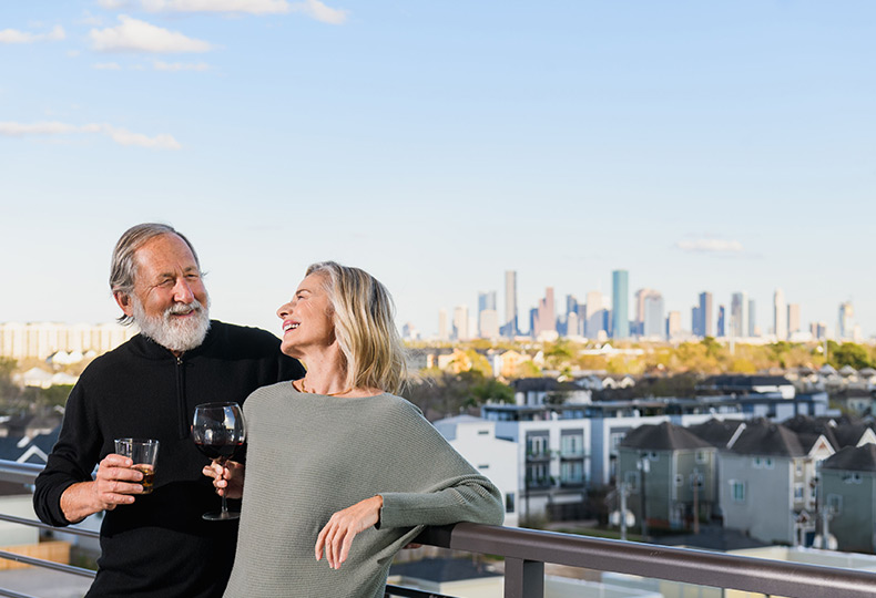 Two residents are on the rooftop patio enjoying a glass of wine and a cocktail.