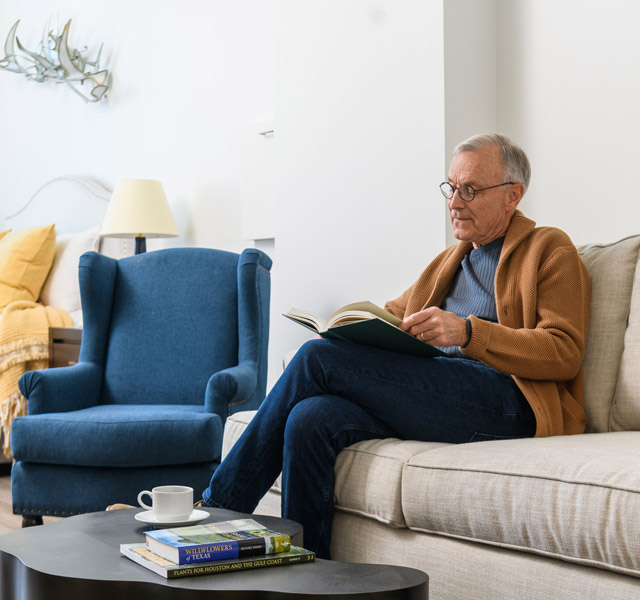 A resident is sitting on a sofa reading a book.