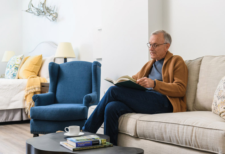 A resident is sitting on a sofa reading a book.