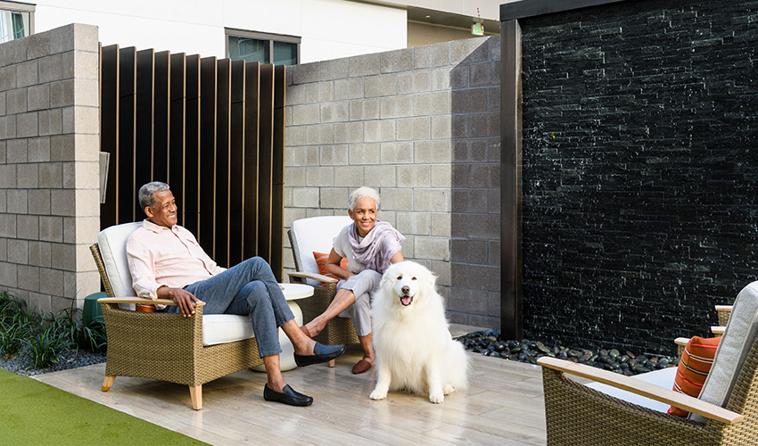 A couple sitting on the patio with their dog.