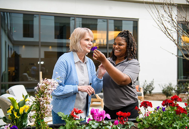 A caregiver holding flowers up for a resident to smell.