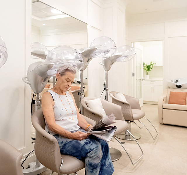 A person sitting under a hair dryer.