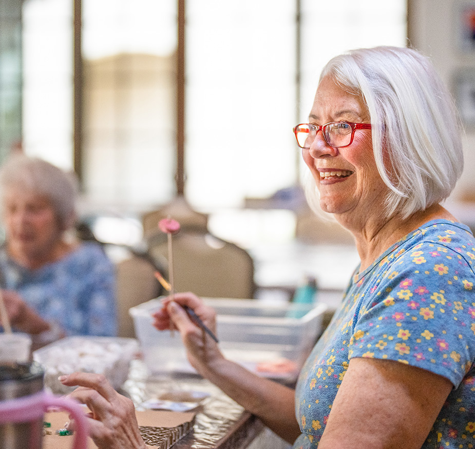 A resident is holding a paintbrush in art class.