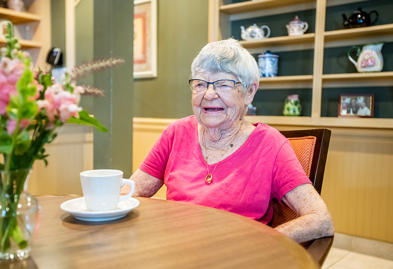 A resident is sitting at a table with a cup of coffee.