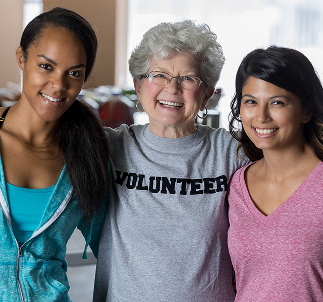 A resident is standing with two volunteers.