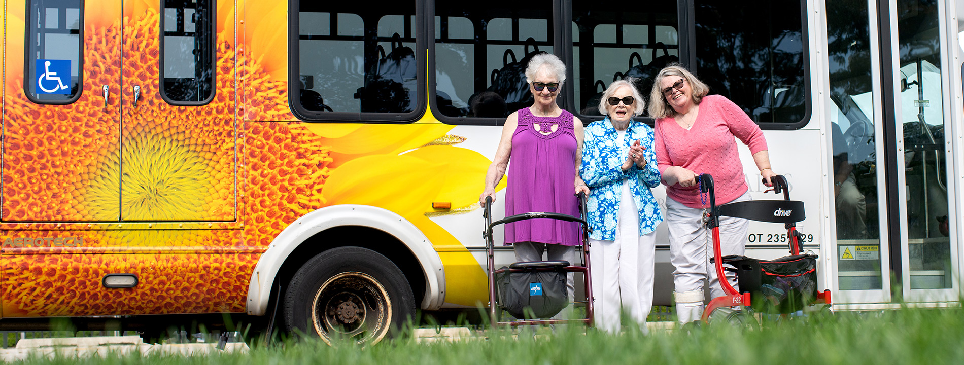 Three residents wearing sunglasses are standing in front of a bus.
