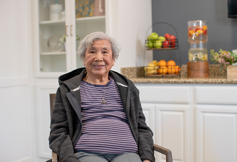 A resident is seated and smiling.