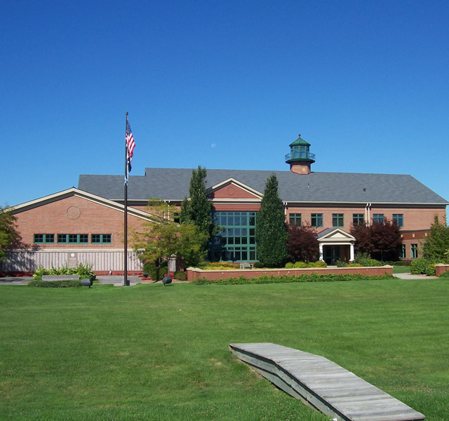 A brick building with a large green front yard.