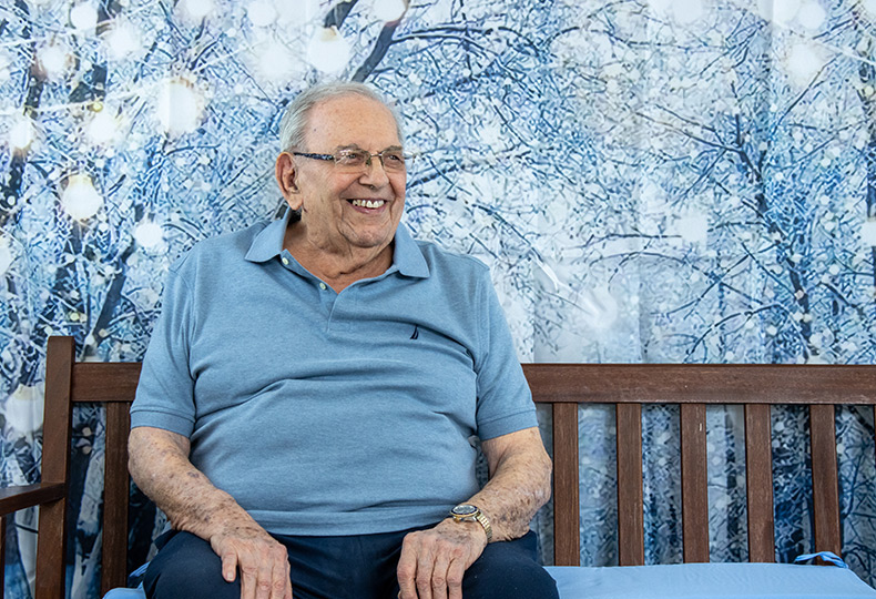 A person on a bench with a wintery woods behind them.
