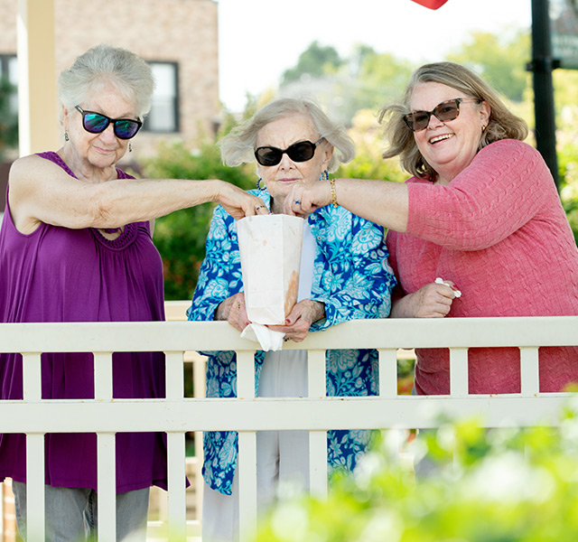 Three residents are wearing sunglasses outside and sharing a snack.