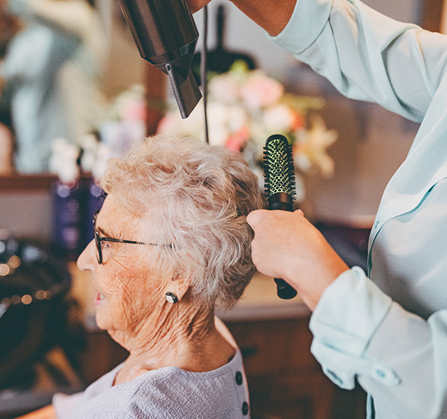 A resident is having their hair cut in the salon.