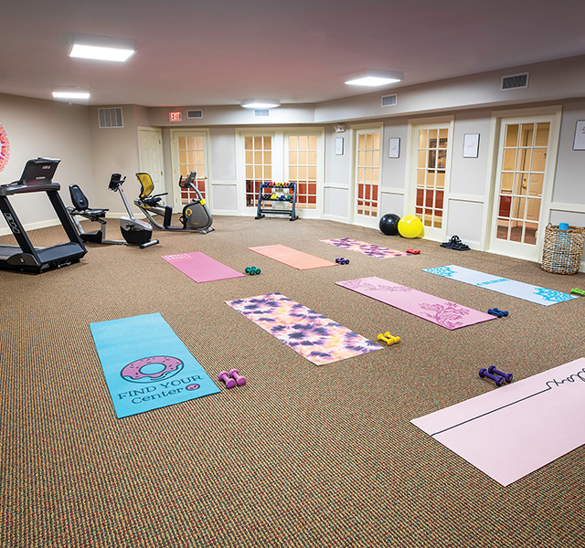 A fitness center with yoga mats on the floor.
