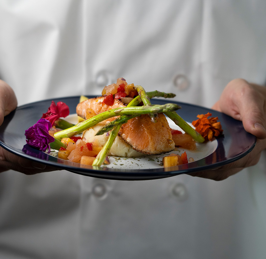 A chef is holding a plate of food.
