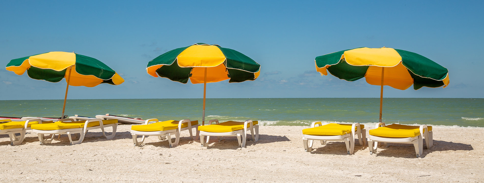 Three beach umbrellas in the sand.