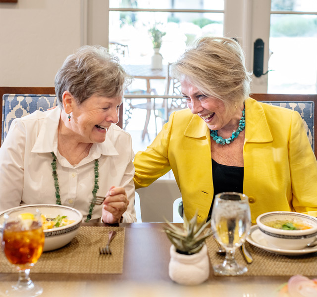 Two residents are eating together in a dining area.