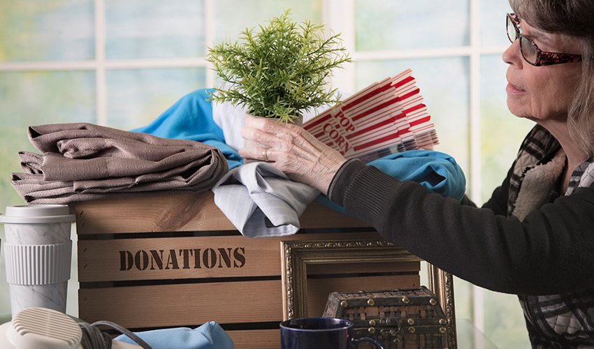 A woman packing a box with items for donation.