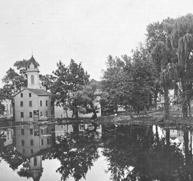 Black and white image of old church by a lake.