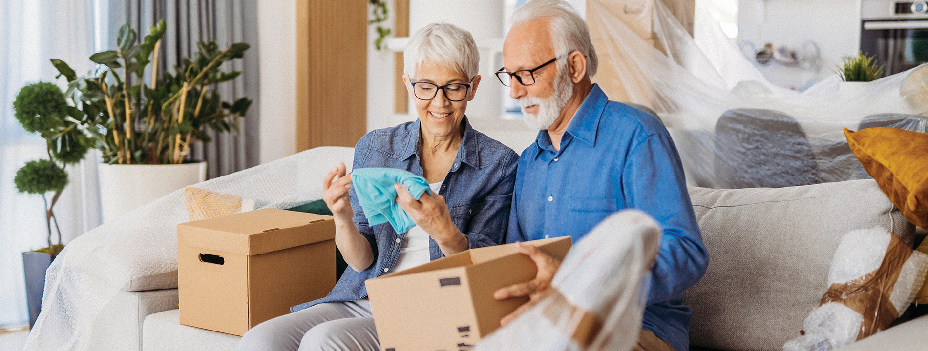 Couple seated on a couch looking through boxes.