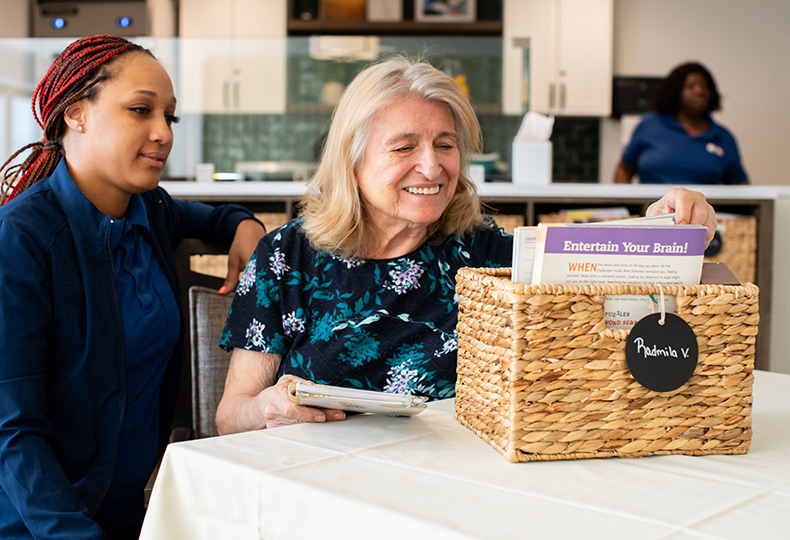 A resident and naya caregiver looking through a basket of personal items.